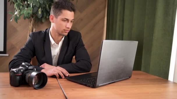 O fotógrafo masculino árabe em uma jaqueta rejeita uma foto no computador portátil e desilude-se. vírus de computador conceito destruiu dados no disco rígido — Vídeo de Stock