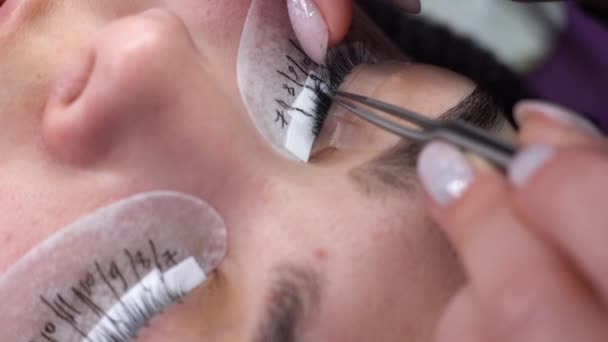 Wimpernverlängerung. drückt der Meister die Wimpern und bereitet die Stelle für die Verlängerung vor. Make-up, Kosmetik. — Stockvideo