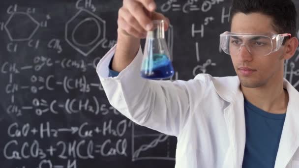 Arabic test tube laboratory assistant. a wide flask in the hands of a chemist. chemistry teacher in a suit and glasses. Handling hazardous liquids. Laboratory assistant studying reagents. — Stock Video