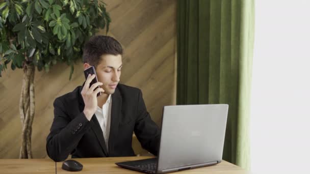 Empresário árabe trabalha em um escritório moderno com um PC e fala ao telefone, trabalhando com um laptop em um café e negociando com parceiros, negócios — Vídeo de Stock