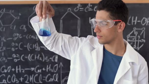 Arabic chemist conducting experiment mixing liquids in flask, laboratory assistant in goggles showing chemical reaction in lesson, chemistry science — Stock Video