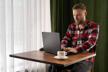 Serbest çalışma konsepti, Kafe 'de dizüstü bilgisayarla çalışan Kafkasyalı serbest çalışan, uzaktan çalışan, klavye bilgisayarında daktilo kullanan, kahve dükkanında oturan, mesaj yazan