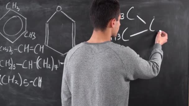 Mans hand draws chemical equations on a blackboard. lesson at school. Arab guy writes a complex equation. — 비디오