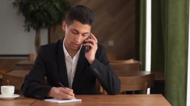 Genç çok ırklı iş adamı telefonda konuşuyor kafede kahve molası veriyor, iş arkadaşlarıyla cep telefonunda iş görüşmeleri yapıyor, konsept girişimcilik yapıyor.