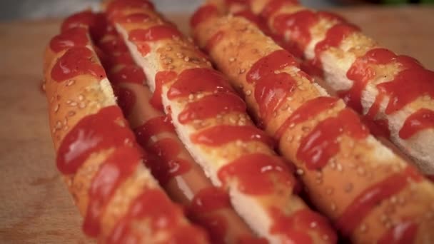 Αργή κίνηση δύο χοτ ντογκ με κέτσαπ ντομάτας στην κορυφή, αμερικανικό φαγητό, ανθυγιεινό λιπαρό δείπνο, σνακ σε ένα κουλούρι με λουκάνικο — Αρχείο Βίντεο