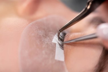 kirpik uzatma prosedürü ana aracı yakın çekim. Uzun kirpikleri var. Kirpik ustasının ofisindeki kanepede güzel bir kız yatıyor..