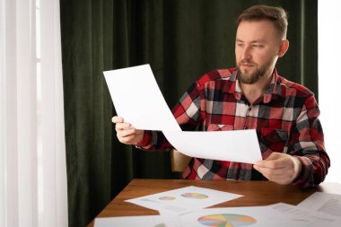 Adam bir ev sigortası ev kredileri üzerinde oturum, kredi yatırım grafik grafik belgeleri ve hesaplama tablosu taksit ödeme, gayrimenkul konsept aracı tutar.