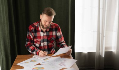 Adam bir ev sigortası ev kredileri üzerinde oturum, kredi yatırım grafik grafik belgeleri ve hesaplama tablosu taksit ödeme, gayrimenkul konsept aracı tutar.