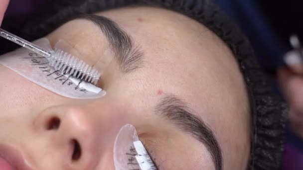 Eyelash extensions in a beauty salon. Ready eyelashes, beautician combing with a special brush, close-up — Stock Video