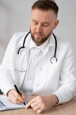 Bir tıp dergisine not alan nitelikli erkek terapist. Odaklanmış genç doktor.