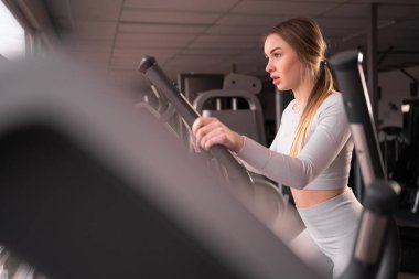 Çekici genç atletik kadın spor salonunda antrenman yapıyor. Kardiyo makinesinde egzersiz yapan bir kadın.