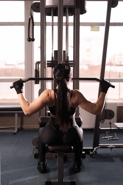 Schultersenkmaschine. Fitness-Frau trainiert im Fitnessstudio. Krafttraining für den oberen Rücken. zurück — Stockfoto