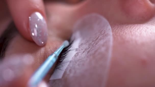 Eyelash extension procedure in spa salon. close-up, master degreases the eyelashes with a solution. — Stock Video