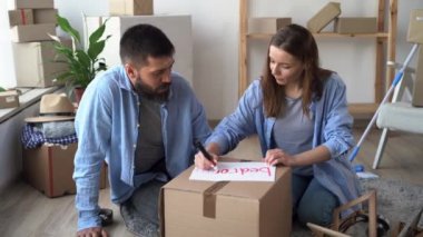 young married couple moves to a new house, packing boxes with things, carrying a bedroom box, relocation and a new apartment, happy home owners