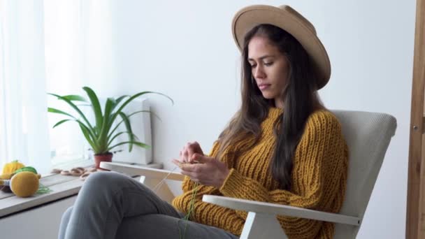 Hobby y concepto de ocio, mujer latina joven tejiendo un suéter de hilos de lana, tejer sentado en una silla, costura — Vídeos de Stock