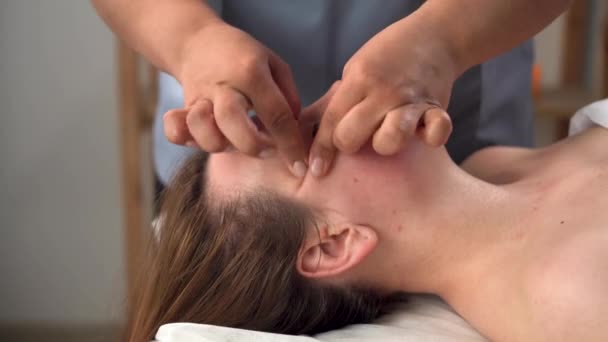 Manual sculpting face massage for young woman in beauty salon, facial action in spa salon, masseur hands working on female face, anti age wrinkle massage, relaxation concept — Stock Video