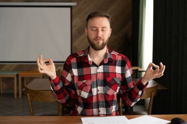 Yakışıklı erkek işadamı rahat bir ofiste otururken meditasyon yapar, meditasyon yapar ve sıkı çalışmanın verdiği rahatlık, dinlenme, girişimci istirahatı, meditasyon konsepti