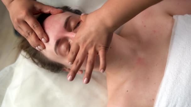Een close-up foto van een vrouw die een gezichtsmassage krijgt. Therapeut oefent druk uit met duimen op voorhoofd en neus, wellness massage — Stockvideo