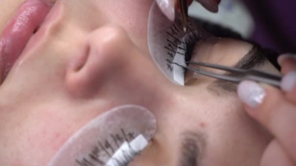 Wimper verlenging meester voert lijmen wimpers close-up. Wimper uitbreiding procedure in een schoonheidssalon — Stockvideo