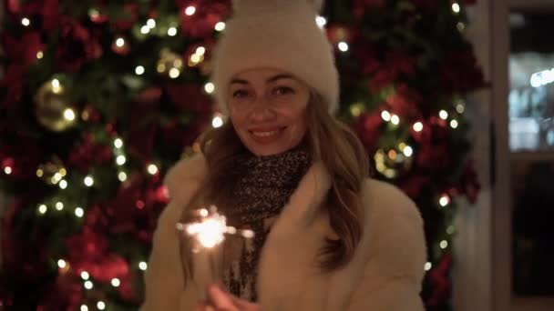 Portret młodej pięknej białej kobiety w kapeluszu stoi na ulicy, trzymając w dłoniach iskry. Koncepcja obchodów Bożego Narodzenia, Nowy Rok. — Wideo stockowe