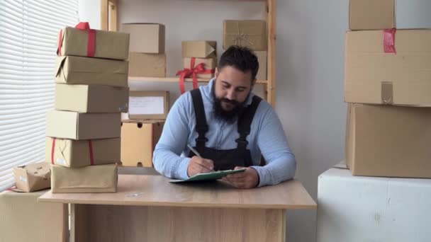 Bearded hindu male business owner working from home in uniform with packing box at workplace - online buying or selling online concept. — Vídeo de Stock