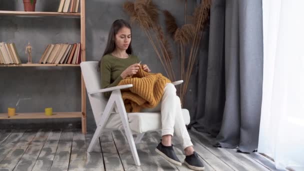 Costura en casa, mujer joven teje un suéter de lana, ropa de punto para los niños, trabajo a mano en agujas de punto, pasatiempo — Vídeos de Stock
