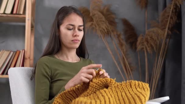 Mujer joven latina tejiendo suéter cálido, accesorios de punto en el hogar, ocio y hobby — Vídeos de Stock