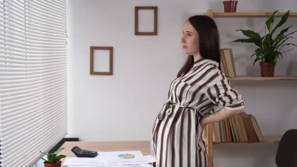 Self - back massage of a pregnant woman working in the office, pregnancy discomfort, lower back massage third trimester, pregnancy and work — Stok video