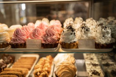 Dükkanda pasta ve hamur işleri olan bir vitrin. Vitrindeki her tat için kek ve hamur işi. Pasta dükkanının vitrininde krema sepeti. Mağazadaki kafede çeşitli pasta ve tatlılar.