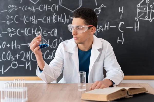 Young Arab Male Chemistry Teacher Sits Table Background Chalk Board — 스톡 사진