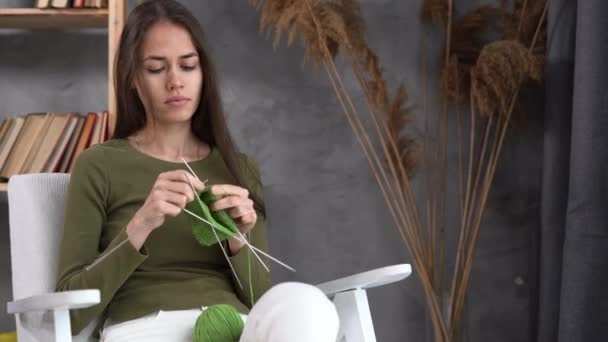 Lateinische Frau strickt mit Nadeln. Handgemacht. Stricknadel. Ein Mädchen strickt einen Schal aus feinem Garn und sitzt in einem gemütlichen Stuhl. Hobby zu Hause — Stockvideo