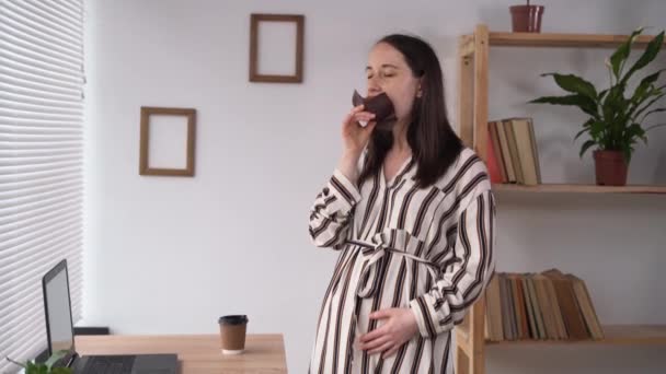 Mujer embarazada comiendo magdalena en la oficina, freelancer femenina teniendo sabroso magdalena en la oficina en casa, nutrición del embarazo y la salud — Vídeos de Stock