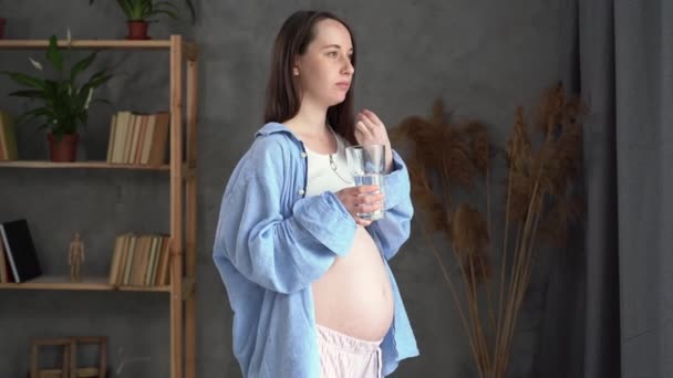 Vážná těhotná žena bere pilulku s vodou, mladá dívka bere doplňky, denní vitamíny pro vlasy a kůži, přírodní krásy, zdravý životní styl a těhotenství — Stock video