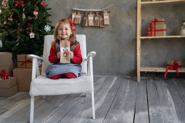 Noel gelenekleri konsepti, el yapımı şeker paketlerinden elde yetişen takvim, elinde tatlı paketi olan mutlu çocuk, çocuksu Noel neşesi