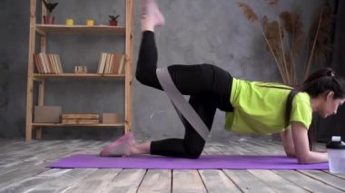 Woman during her fitness workout at home with rubber resistance band, home sport