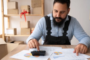 Yakın plan, Hintli işadamı makineyle hesaplama yapıyor, evdeki mali riskleri yönetiyor, çift ırklı adama odaklanmış hesap makineleri, faturalar, vergiler veya harcamalar üzerinde hesaplamalar yapıyor, ofisteki insan analizleri