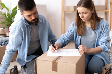 Mutlu kadın yatak odası kelimesini kırmızı kalemli şeylerin olduğu bir kutuya yazıyor. Yeni bir daireye taşınma fikri. Boşluğu kopyala.