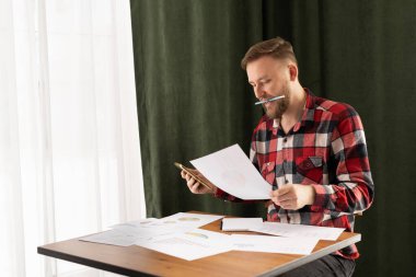 Günlük hayatta olan beyaz adam pazarlama araştırma raporlarına bakıyor, grafiklerdeki istatistiksel verileri analiz ediyor, büyüme stratejisini geliştiriyor, tek başına çalışıyor.