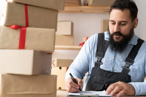 indian small business owner working from home office, start-up shipping and delivery business, male entrepreneur or warehouse worker preparing online shipping delivery parcels boxes. sme concept