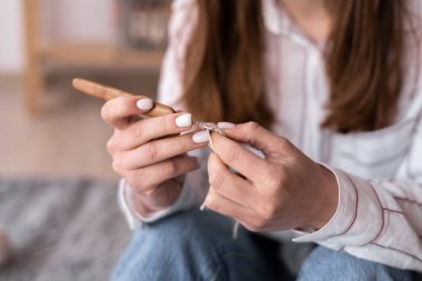 Örgü ören ellerin yakın çekimi, atkı ören genç bir kadın, hobi ve eğlence konsepti.