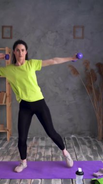 Spor salonundaki kadın evde kol kası egzersizi için halterleri kaldırıyor. Latin kadın vücut geliştirici, dambıllı bisepsler, evde egzersiz, fitness konsepti