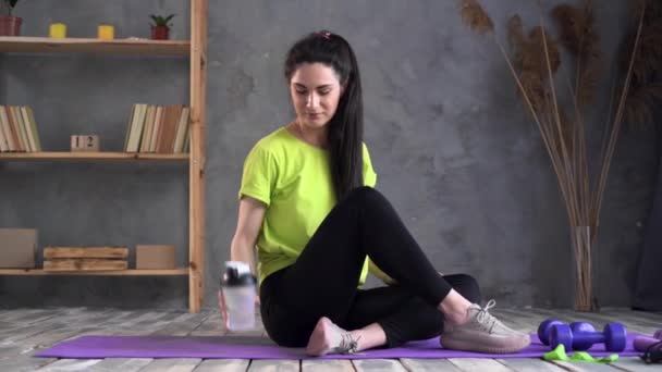 Mujer latina bebiendo agua después de entrenar en una esterilla deportiva, joven atleta haciendo yoga y gimnasia. concepto de bienestar. Clases de deportes individuales. — Vídeo de stock