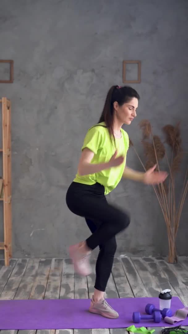 Young latina woman in sportswear doing morning yoga at home, standing on fitness mat and stretching her legs and arms, side view, healthy lifestyle, sport, fitness concept — Stok video