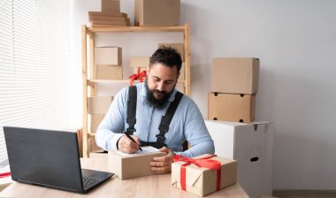 Start-up small business SME owner Indian man entrepreneurs, write the address on receipt box and check online orders, prepare to pack boxes, selling online, e-commerce, SME business online concept.