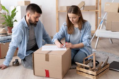 Taşınma günü ve taşınma konsepti, yeni taşınma gününde karton kutuları yeni eve paketleyen kadın ve erkek, yeni bir daire için eşyalar.