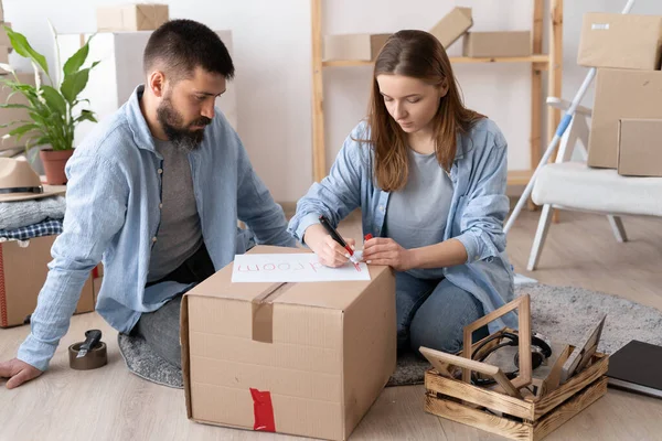 Taşınma günü ve taşınma konsepti, yeni taşınma gününde karton kutuları yeni eve paketleyen kadın ve erkek, yeni bir daire için eşyalar.