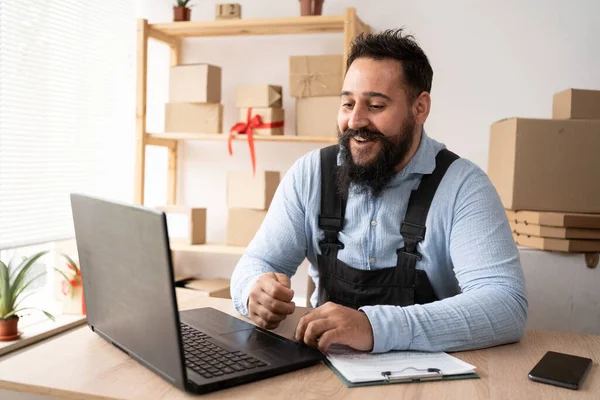 bearded indian male entrepreneur working with laptop, young small business owner selling online on website. Internet sales, online sale, e-commerce, online business, postal parcel, delivery concept.