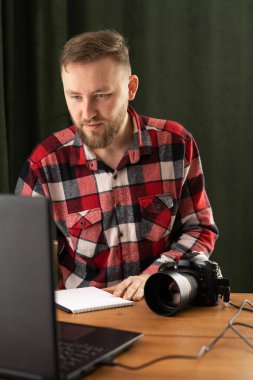 Professional photographer with camera and laptop computer working at studio. Photographer with assistant sitting in office and looking at camera. copy space