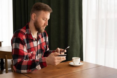 Happy caucasian man holding mobile phone typing card data to make online payment sitting in cafe, online shopping concept