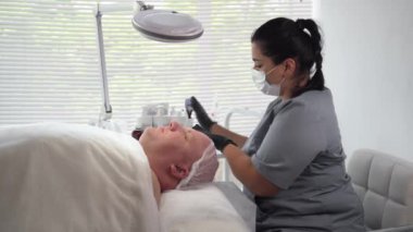 Kozmetik uzmanı spa salonundaki erkeklerin yüzüne kozmetik maske takıyor.